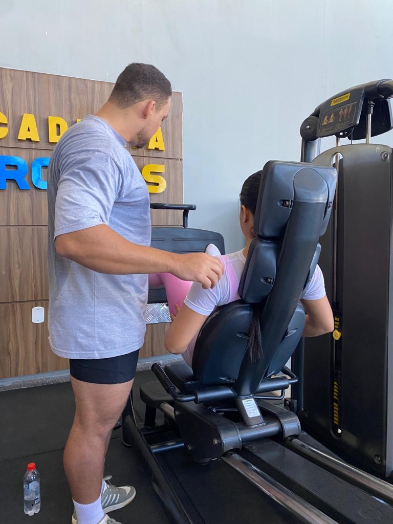 Jhone Max orientando aluna no leg press